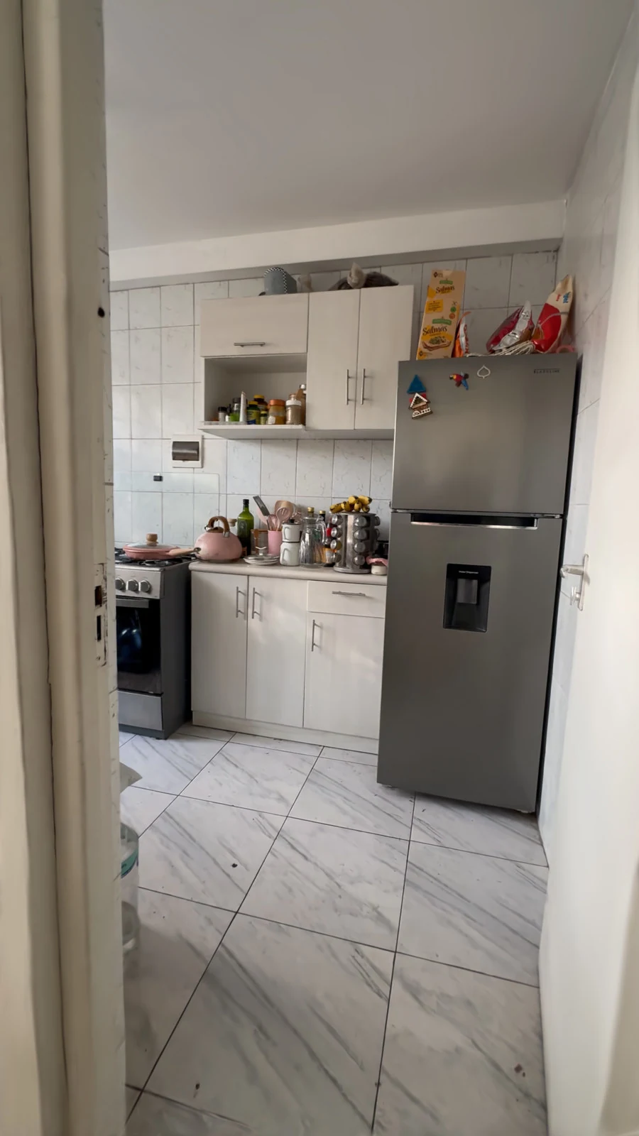 La entrada de la cocina, con refrigeradora, muebles y piso de mayólica.